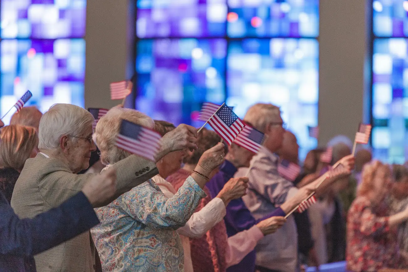 A group of people holding american flags in front of their faces.